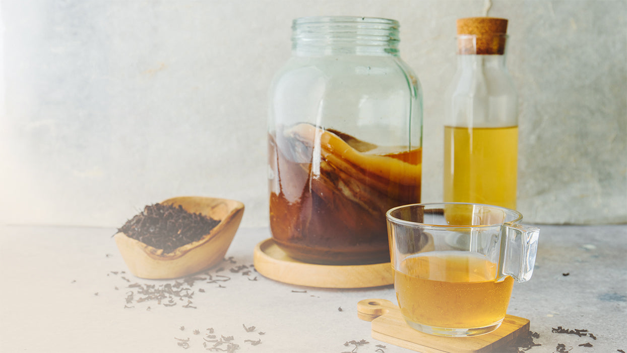 Glasgefaess mit Scobs Flasche Glas mit Kombucha Holzschale mit Tee