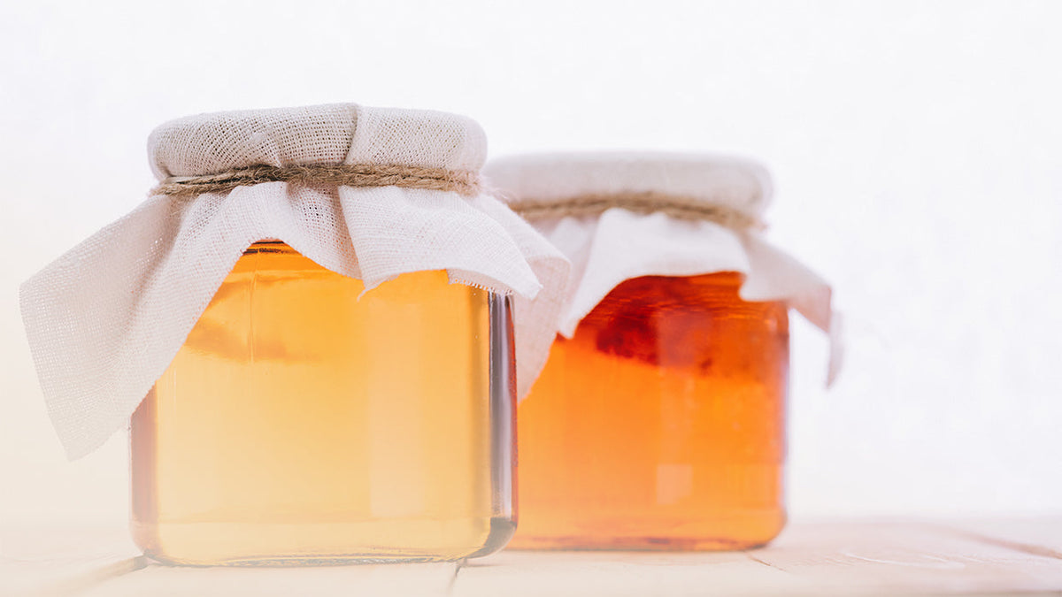 Zwei Einmachglaeser mittelgross mit Kombucha mit Tuechern abgedeckt